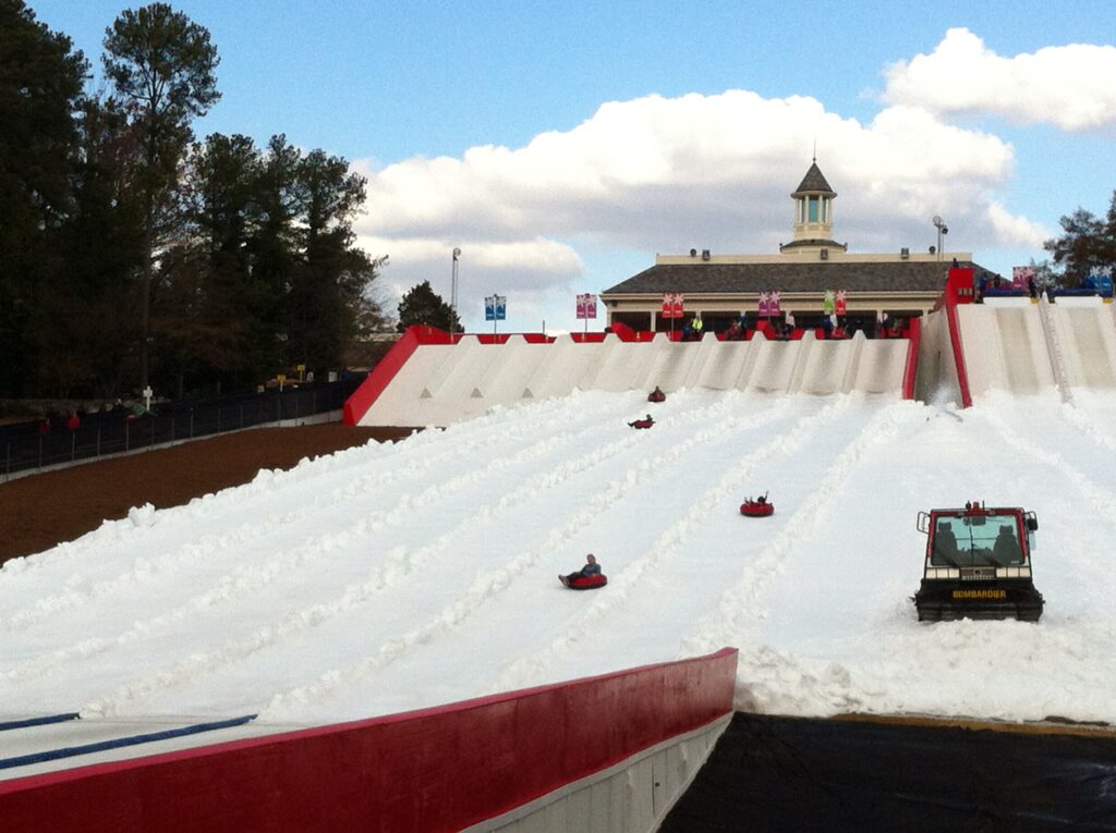 People riding snow tubes down manmade snow slides at Stone Mountain Park
